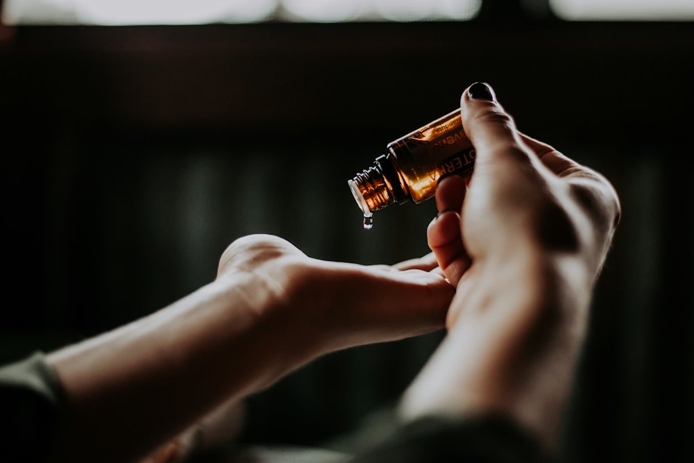 Hands holding an amber bottle of massage oil